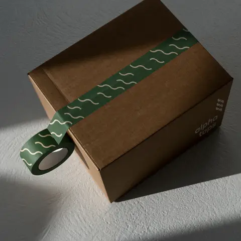 Identité visuelle de Alpha Tops utilisée sur un carton d'expédition et son ruban adhésif coloré